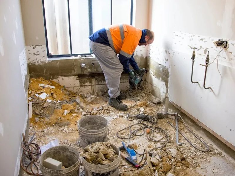 Operario retirando el suelo y el alicatado de un baño durante la fase de demolición de una reforma