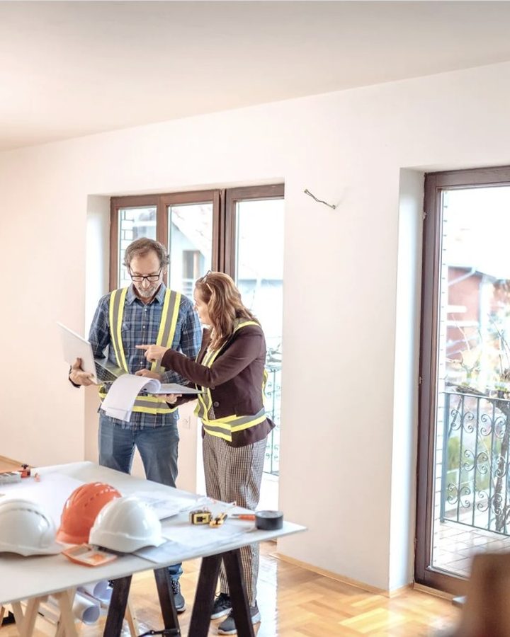 Técnicos de Reformas Huelva con casco revisando los planos de una reforma en la vivienda