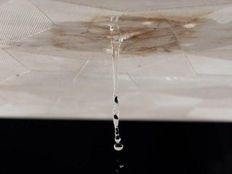 Gota de agua cayendo de un techo manchado por una filtración