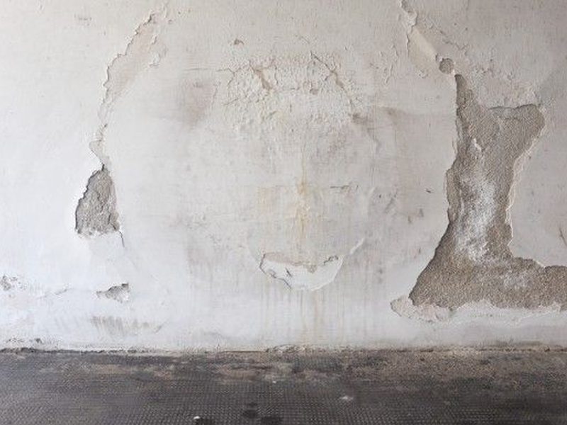 Pared interior con el enlucido desprendido por la humedad en una casa antigua