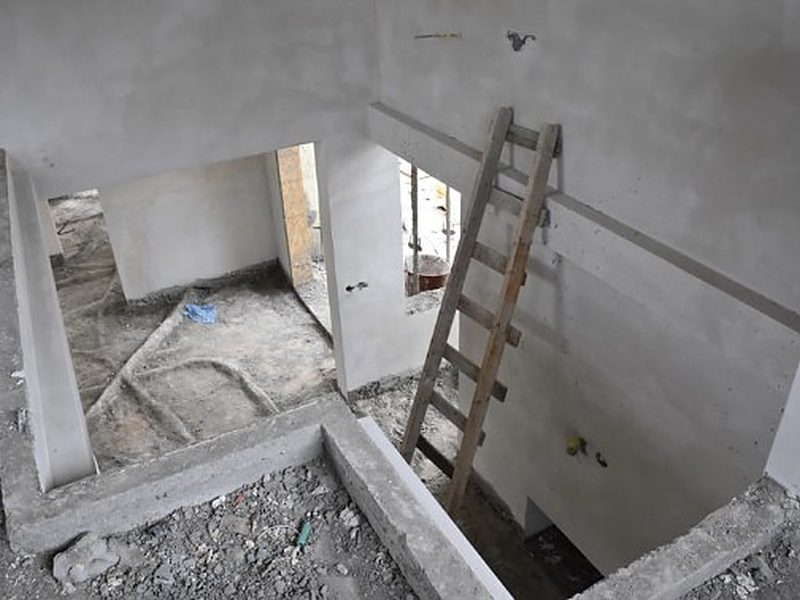 Vivienda en fase de derribo con forjado al descubierto, hueco de escalera y escalera de mano