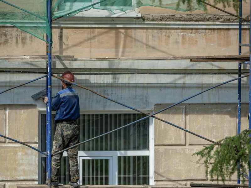 Operario sobre andamio con red de protección rehabilitando la fachada de un edificio