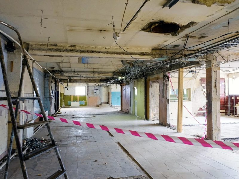 Local comercial en desmontaje con techo abierto, cableado antiguo y zona balizada