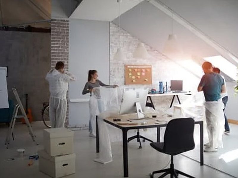 Pintores y montadores terminando una oficina con puestos de trabajo y pared de ladrillo visto