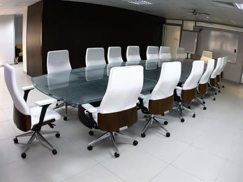 Sala de reuniones de una oficina reformada con mesa de vidrio y sillas blancas