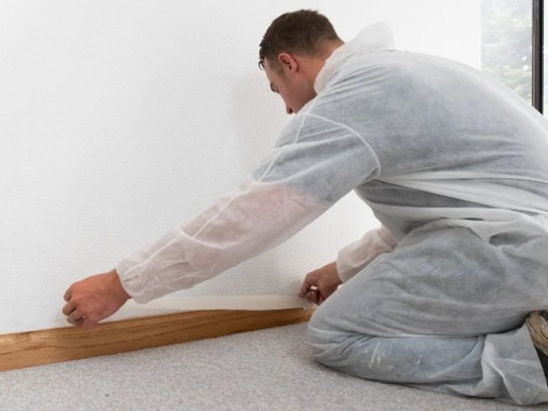 Instalador colocando el rodapié sobre un suelo de parquet recién instalado