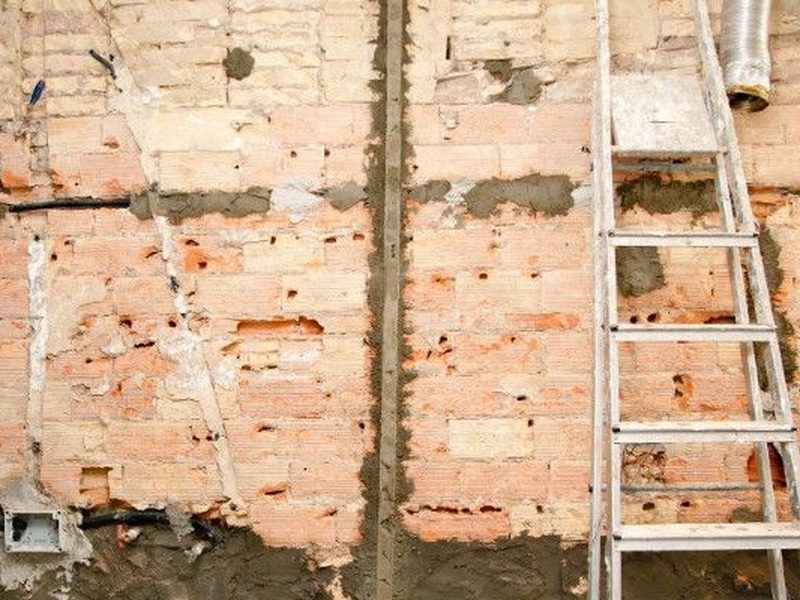 Pared de ladrillo antiguo con rozas abiertas para renovar las instalaciones