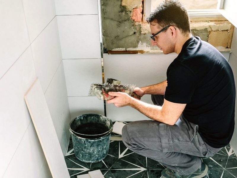 Operario reparando azulejos en un baño