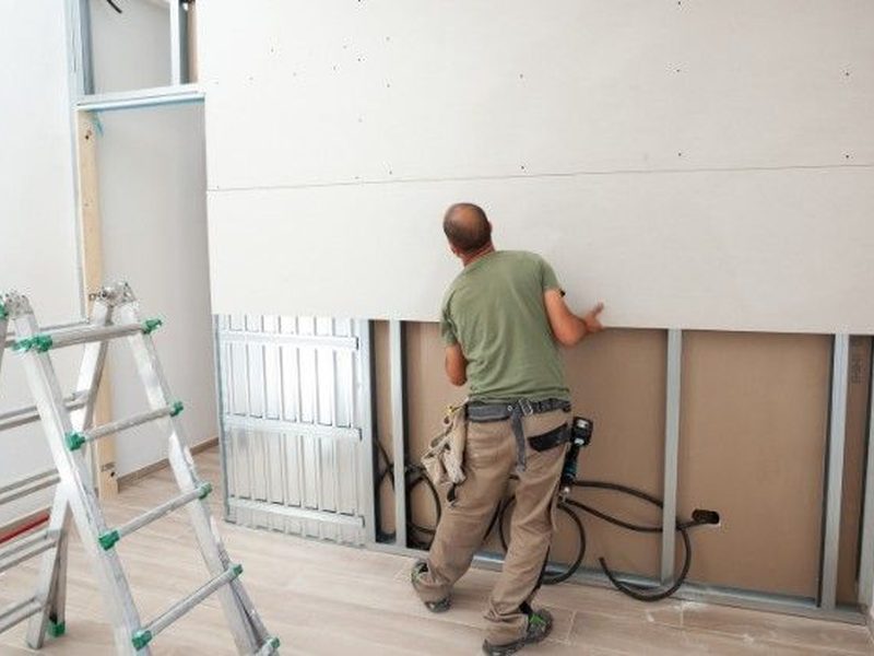 Instalador atornillando placas de pladur sobre perfilería metálica